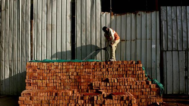 A worker waters a stack of bricks at a construction site in New Delhi. India’s economic growth slowed marginally to 7% in October-December from 7.4% in the previous quarter after the controversial ban on high-value banks notes in November.(AFP)