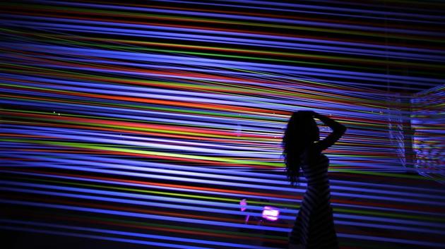 A woman poses in front of a light art piece titled ‘Horizontal Interference’ by artists Katarzy Malejka and Joachim Stugocki of Poland. (Wong Maye-E / AP)