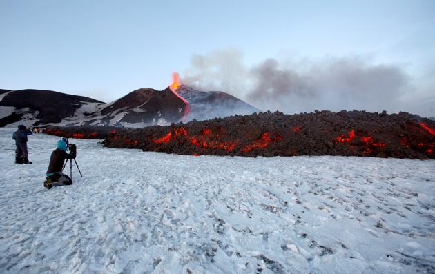 Tourists taking pictures of the pouring lava coming out of Mount Etna. (Antonio Parrinello / REUTERS)