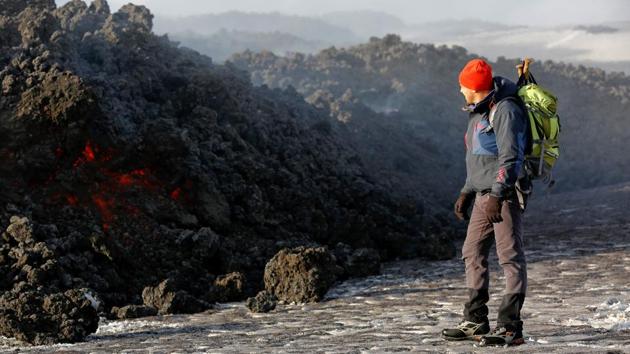 Volcano guide stands in front of lava pouring from Italy's Mount Etna. (Antonio Parrinello / REUTERS)