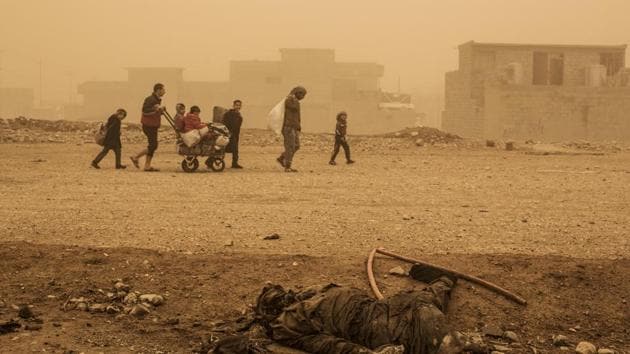 In this December 2, 2016 file photo, a group of civilians pass close to the body of an Islamic State militant, while fleeing from Mosul due to ISIS heavy shelling in several areas under control of the Iraqi Army, Mosul, Iraq.(AP)