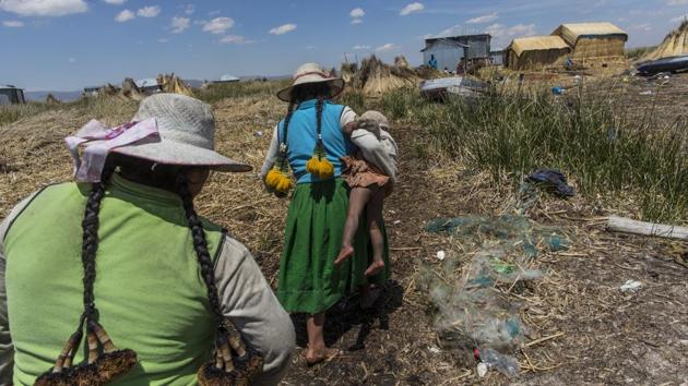 A woman carries her baby home in Kapi Cruz Grande, a village on the trash filled shores of Lake Titicaca. Peru’s new president, Pedro Pablo Kuczynski, a former Wall Street banker who lived just 40 kilometers (25 miles) from the lake as a youth, has made access to clean water one of the priorities of his presidency. (Rodrigo Abd/AP) A woman carries her baby home in Kapi Cruz Grande, a village on the trash filled shores of Lake Titicaca. Peru’s new president, Pedro Pablo Kuczynski, a former Wall Street banker who lived just 40 kilometers (25 miles) from the lake as a youth, has made access to clean water one of the priorities of his presidency. (Rodrigo Abd/AP)
