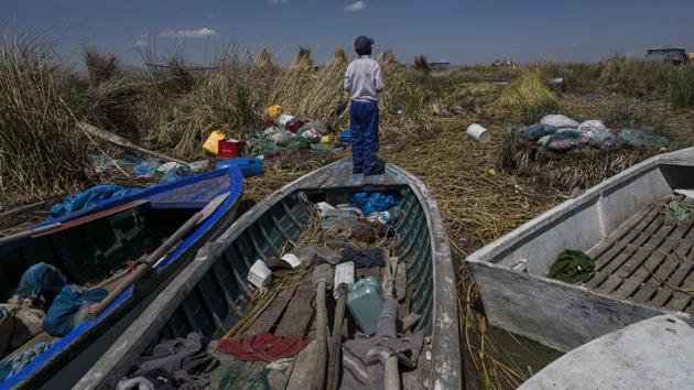 A boy stands on a fishing boat on the littered shore of Lake Titicaca in Kapi Cruz Grande. The camouflage coloured Titicaca water frogs that used to be in abundance have thinned in numbers and have been placed on a “critically endangered” list by the International Union for Conservation of Nature and just 10,000 remain. (Rodrigo Abd/AP) A boy stands on a fishing boat on the littered shore of Lake Titicaca in Kapi Cruz Grande. The camouflage coloured Titicaca water frogs that used to be in abundance have thinned in numbers and have been placed on a “critically endangered” list by the International Union for Conservation of Nature and just 10,000 remain. (Rodrigo Abd/AP)