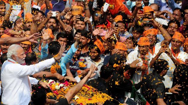 Prime Minister Narendra Modi waves to supporters during his roadshow in Varanasi on Saturday.(AFP)