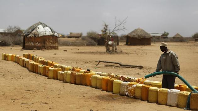A man fills a long line of plastic water containers from a tanker, in the drought-affected village of Bandarero. (Ben Curtis / AP) 