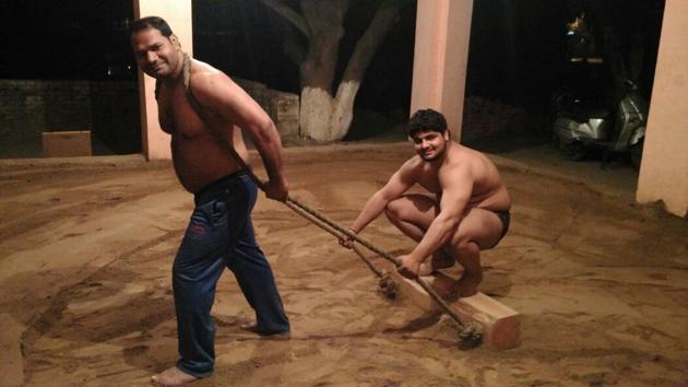Ashok Pehelwan levels the soil of akhada by pulling a wooden log. (HT Photo) Ashok Pehelwan levels the soil of akhada by pulling a wooden log. (HT Photo)
