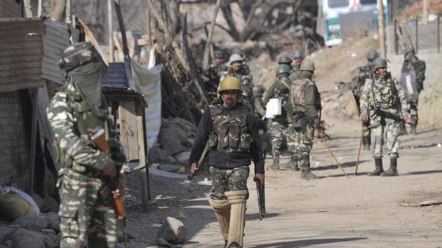 Security personnel stand close to the site of a gunfight in south Kashmir’s Tral on Sunday.(Waseem Andrabi / HT Photo)