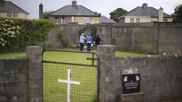 People gather at the site of a mass grave for children who died in the Tuam mother and baby home in Tuam in County Galway. (AP) People gather at the site of a mass grave for children who died in the Tuam mother and baby home in Tuam in County Galway. (AP)