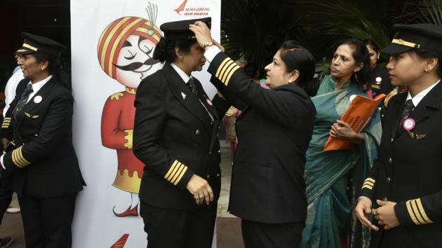 A pilot adjusts the cap of another colleague during the ceremony. AI is marking International Women’s day by flying 10 ‘All Women operated’ flights on its international and domestic routes. (Vipin Kumar/HT PHOTO)
