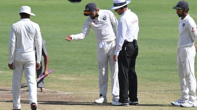India captain Virat Kohli points out crumbled parts of the pitch to umpire Richard Kettleborough during the Pune Test last month.(AFP)
