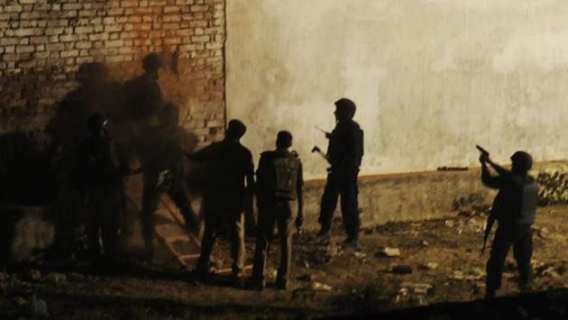 Police officers make a hole in a wall of the building where the suspect was hiding to send in optical fibre cameras. (deepak gupta/ht photo) 