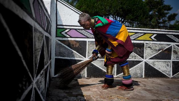 Esther Mahlangu, sweeps the floor of her home in Mabhoko Village, Siyabuswa. (GULSHAN KHAN / AFP) 