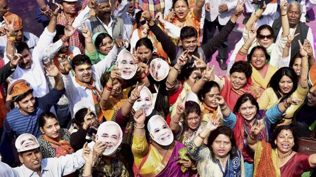 BJP supporters celebrate the party’s victory in the Uttar Pradesh assembly elections wearing masks of Prime Minister Narendra Modi in New Delhi on Saturday.(PTI photo)