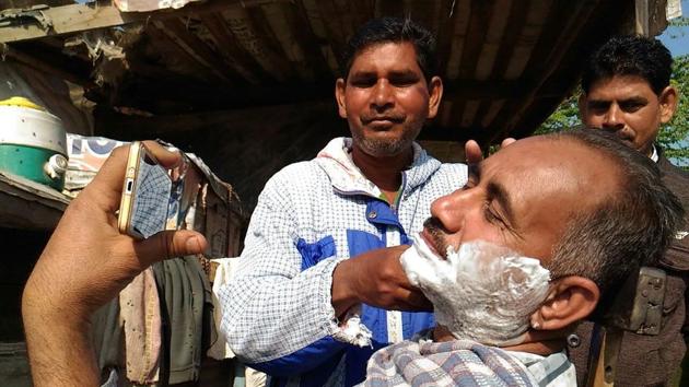A man at roadside salon watching election results on mobile phone during a shave outside a counting centre in Fazilka, Punjab. (Anil Dayal/Ht Photo) A man at roadside salon watching election results on mobile phone during a shave outside a counting centre in Fazilka, Punjab. (Anil Dayal/Ht Photo)