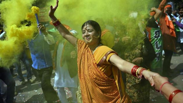 A supporter of BJP celebrates outside the party headquarters in New Delhi after the elections results were announced.(AFP)