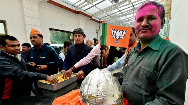 A BJP worker holds a huge laddu during celebrations after the party’s victory in UP and Uttarakhand assembly elections, at the party headquarters in New Delhi on Saturday.(PTI)