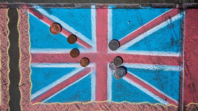Pound sterling coins are pictured on a chalk drawing of a Union flag on the pavement in Trafalgar Square in London.(AFP File Photo)