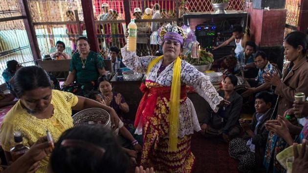 Devotees watch a medium invoke spirits inside a shrine in Shwe Ku Ni. Beggars dressed up as Nats and clutching wooden bowls line the road as they seek donations from the devotees. (Ye Aung Thu/AFP) Devotees watch a medium invoke spirits inside a shrine in Shwe Ku Ni. Beggars dressed up as Nats and clutching wooden bowls line the road as they seek donations from the devotees. (Ye Aung Thu/AFP)