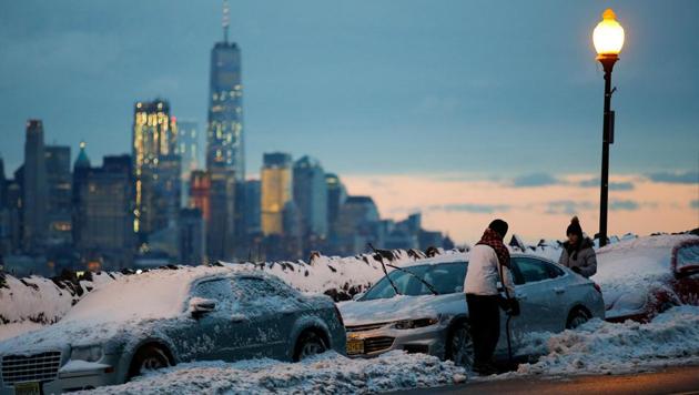 Residents clear their cars and street of snow in Weehawken, New Jersey, as the One World Trade Center and lower Manhattan are seen after a snowstorm in New York, U.S. (Eduardo Munoz/REUTERS)