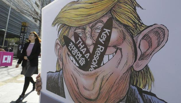 A woman walks by a poster with an illustration of US President Donald Trump held by a protester during a rally to oppose a plan to deploy an advanced US missile defence system called Terminal High-Altitude Area Defense (THAAD), near the US Embassy in Seoul, South Korea, on March 14, 2017. (AP Photo) A woman walks by a poster with an illustration of US President Donald Trump held by a protester during a rally to oppose a plan to deploy an advanced US missile defence system called Terminal High-Altitude Area Defense (THAAD), near the US Embassy in Seoul, South Korea, on March 14, 2017. (AP Photo)