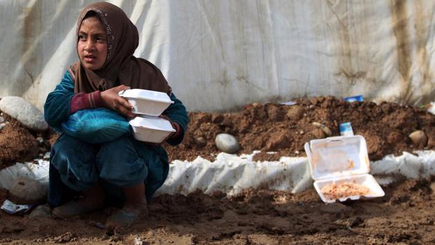 An Iraqi girl, displaced from Mosul, carries food rations as she sits near a tent at the Hammam al-Alil camp for the internally displaced, south of Mosul. (AHMAD AL-RUBAYE / AFP)