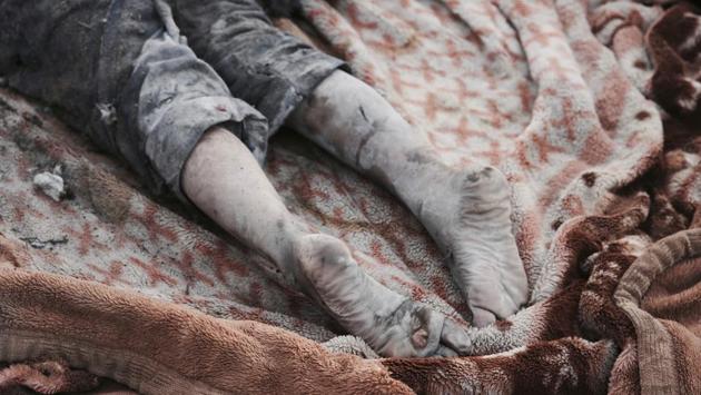 A body lies in a blanket at the site of a mass grave containing some two dozen people, many of them children, in an area recently re-taken from Islamic State militants in Mosul, Iraq. (Christian Stephen / AP)