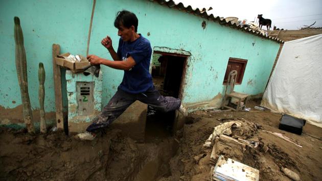 A resident jumps next to his destroyed home after rivers breached their banks due to torrential rains, causing flooding and widespread destruction in Cajamarquilla, Lima in Peru. (Mariana Bazo/REUTERS) 