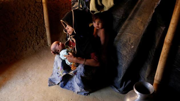Marijaan, 20, holds her 25-day-old daughter Noor Habi as her son stands inside their shelter in Kutupalang unregistered refugee camp in Cox’s Bazar. Marijaan fled to Bangladesh from Khyeri Prang village in Myanmar one month ago after her house was burnt down the by Myanmar military. ‘I reached the border at night and crossed by the boat. I paid the boatman to cross the Naf River,’ Marijaan said. (Mohammad Ponir Hossain/REUTERS)