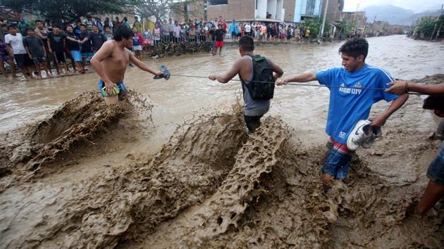 Residents cross a flooded street using a rope. The highly unusual rains follow a series of storms that have struck hard along Peru’s northern coast, with flood waters inundating hospitals and leaving some small villages isolated.  (Douglas Juarez/REUTERS) 