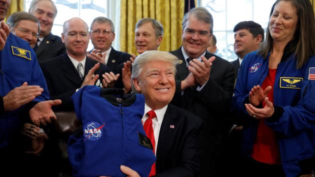 US President Donald Trump receives a NASA jacket during a signing ceremony for S442, the NASA transition authorization act, in the Oval Office of the White House. (REUTERS) US President Donald Trump receives a NASA jacket during a signing ceremony for S442, the NASA transition authorization act, in the Oval Office of the White House. (REUTERS)