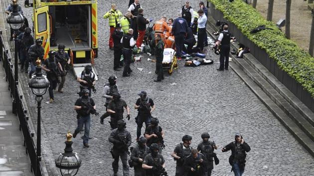 Armed police walk past emergency services attending to injured people on the floor outside the Houses of Parliament, London, Wednesday, March 22, 2017.(AP)