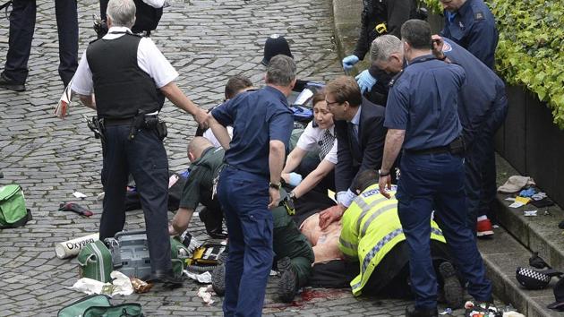 Conservative MP Tobias Ellwood (centre) helps emergency services attend to an injured person outside the Houses of Parliament, on March 22, 2017.(AP Photo)