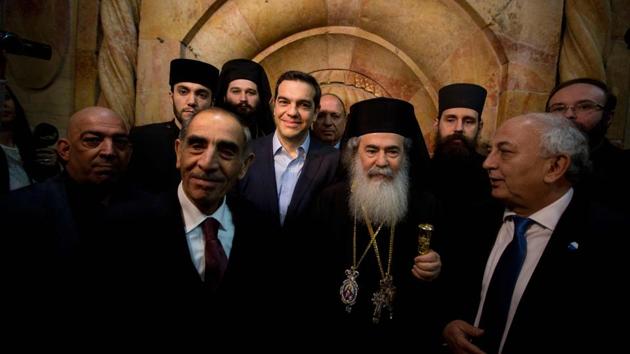 Greek Prime Minister Alexis Tsipras (C) and Greek Orthodox Patriarch of Jerusalem Theophilos III (C-R) walk out of the Edicule following a ceremony at the Church of the Holy Sepulchre. A small window has been cut open into marble slabs to allow pilgrims a glimpse of the rock. The distasteful iron caging around the monument and dark black marks from candles burnt by pilgrims have all disappeared from the structure with the restorers stabilizing the shrine with titanium bolts and mortar and cleaning up thick layers of candle soot and pigeon droppings. (Sebastian Scheiner/AFP) Greek Prime Minister Alexis Tsipras (C) and Greek Orthodox Patriarch of Jerusalem Theophilos III (C-R) walk out of the Edicule following a ceremony at the Church of the Holy Sepulchre. A small window has been cut open into marble slabs to allow pilgrims a glimpse of the rock. The distasteful iron caging around the monument and dark black marks from candles burnt by pilgrims have all disappeared from the structure with the restorers stabilizing the shrine with titanium bolts and mortar and cleaning up thick layers of candle soot and pigeon droppings. (Sebastian Scheiner/AFP)