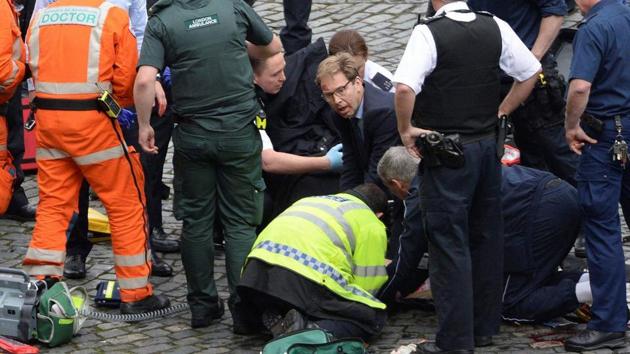 Conservative Member of Parliament Tobias Ellwood, centre, helps emergency services attend to an injured person outside the Houses of Parliament, London, Wednesday, March 22, 2017. (AP)