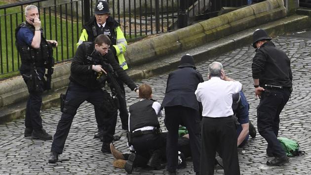 A policeman points a gun at a man on the floor as emergency services attend the scene outside the Palace of Westminster, London, Wednesday, March 22, 2017. (Stefan Rousseau / AP)
