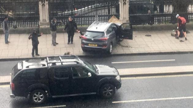 People stand near a crashed car and an injured person lying on the ground, right, on Bridge Street near the Houses of Parliament in London, Wednesday, March 22, 2017. (James West / AP)