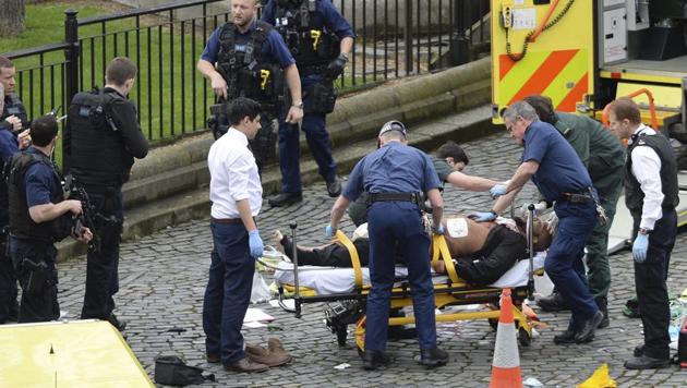 A man is treated by emergency services as police look on at the scene outside the Houses of Parliament London, Wednesday, March 22, 2017. (Stefan Rousseau / AP)