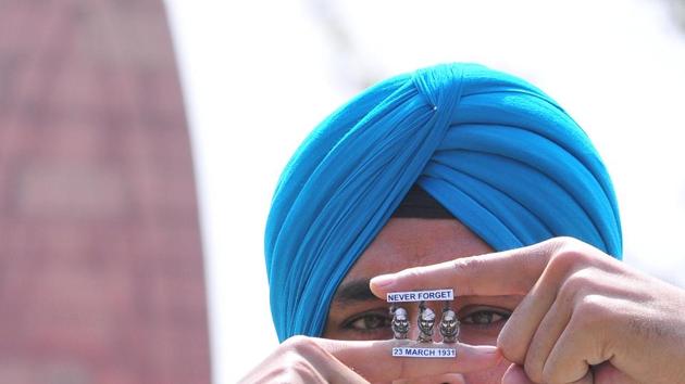 An artist Gurpreet Singh pays  his tribute to martyr Shaheed Bhagat Singh, Rajguru and Sukhdev by making a tiny paper  miniature  at Jallianwala Bagh, Amritsar . (Sameer Sehgal / HT Photo) 