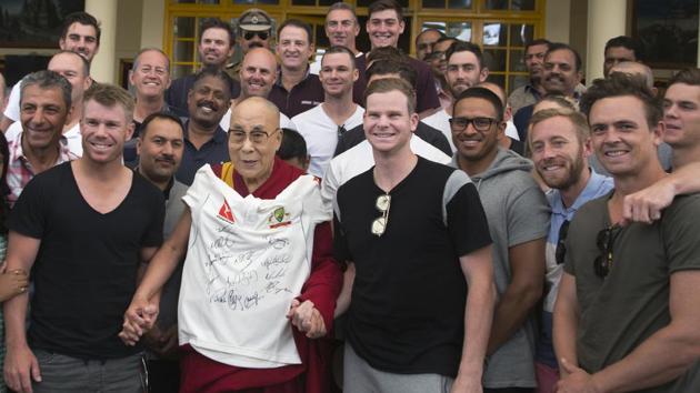The Dalai Lama slings a t-shirt signed by the Australian cricket team players as he poses for a photograph. (AP) 