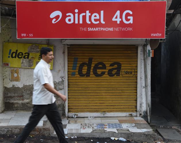 Man walking past a shop with an advertisement for mobile service provider Airtel and Idea in Mumbai. Buyouts, mergers and quick exits -- as India's richest man shakes up the country's ultra-competitive mobile market, telecommunications companies are scrambling to either consolidate or cut their losses and run.(AFP)