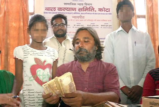 Child Welfare Committee chairman Harish Gurubakshani holds the bundle of banned notes with the two kids (faces blurred) by his side in Kota. (HT Photo) Child Welfare Committee chairman Harish Gurubakshani holds the bundle of banned notes with the two kids (faces blurred) by his side in Kota. (HT Photo)