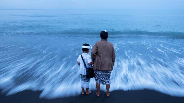 A Balinese Hindu woman hold her grandson's hand on a beach during Melasti, a purification ceremony ahead of the holy day of Nyepi, in Gianyar, Bali, Indonesia March 25, 2017.  (Agung Parameswara / REUTERS) 