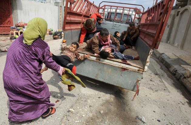 EDITORS NOTE: Graphic content / An Iraqi woman pulls a child, who was injured by a mortar shell fired by Islamic State (IS) group jihadists on a civilian gathering, off the back of a pick up truck in Al-Risala neighbourhood on March 22, 2017, as an ongoing offensive by Iraqi forces to retake the city from the group continues. Iraqi forces launched a major operation to recapture west Mosul -- the most-populated urban area still held by IS -- on February 19, and have retaken a series of neighbourhoods from the jihadists. 