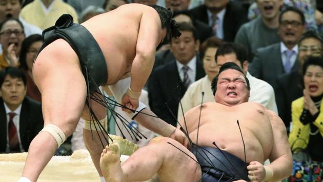Japanese Yokozuna or sumo grand champion Kisenosato (R) is thrown out of the ring by Mongolian Yokozuna Harumafuji (L) at the Spring Grand Sumo Tournament in Osaka on March 24, 2017. (AFP) 