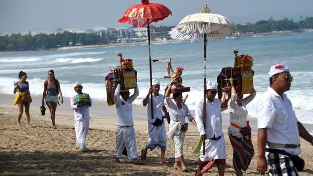 Balinese people walk along Kuta beach to attend prayers for the Melasti ceremony. (Sonny Tumbelaka/AFP) Balinese people walk along Kuta beach to attend prayers for the Melasti ceremony. (Sonny Tumbelaka/AFP)