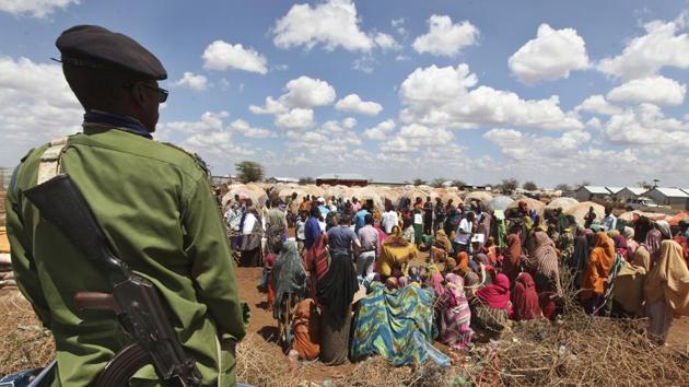 A Somali policeman provides security as displaced Somalis gather outside their makeshift shelters at a camp in Baidoa, Somalia. (Farah Abdi Warsameh/AP)