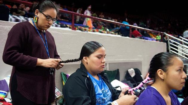 Sunshine Hayes (L) braids her sister Skye's hair, while Skye does the same for Ariana Hollow Horn, prior to the start of the 43rd Annual Denver March Powwow. (Jason Connolly / AFP)