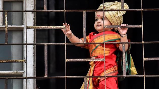 This cute picture in red held on to her window to see a procession celebrating 'Gudhi Padwa' or the Maharashtrian New Year from her balcony in Girgaum. (Kunal Patil/HT Photo) 