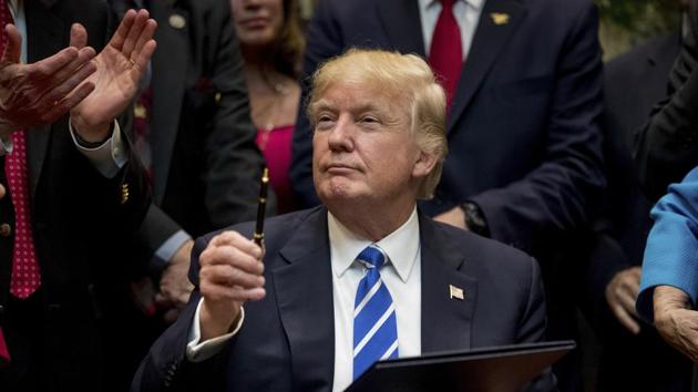 In this March 27 photo, President Donald Trump holds up a pen he used to sign one of various bills in the Roosevelt Room of the White House in Washington.(AP)