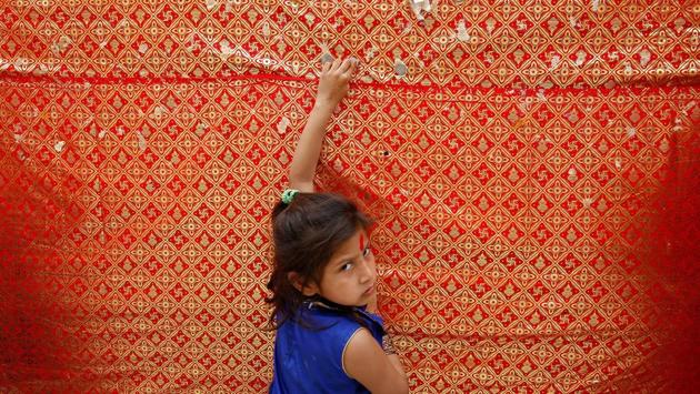 A girl looks on as she sticks a coin on the wall of a temple on the first day of Navratri festival in Jammu. (Mukesh Gupta / REUTERS)